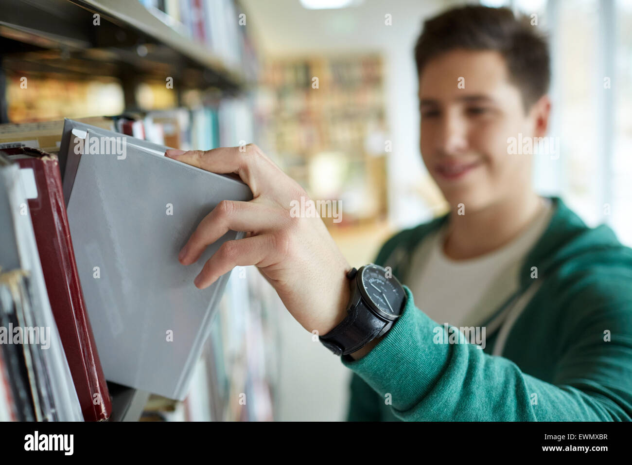 Close up di felice studente Ragazzo con libro in biblioteca Foto Stock