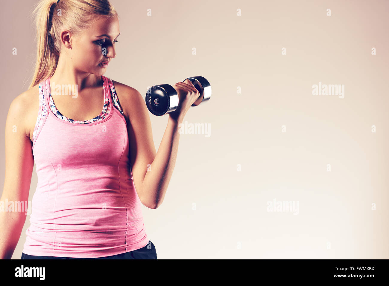 Giovane donna esercita il corpo superiore facendo un bicipite curl con un peso libero. Foto Stock