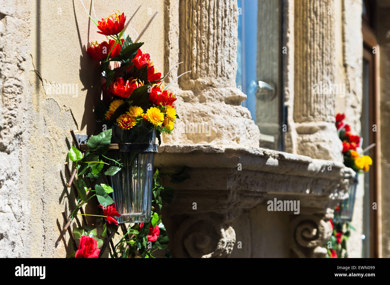 Bellissimi fiori rossi e gialli, rose rosse e pietra bianca del vecchio edificio, dettaglio dalle strade di Ortigia, Siracusa, Sicilia Foto Stock