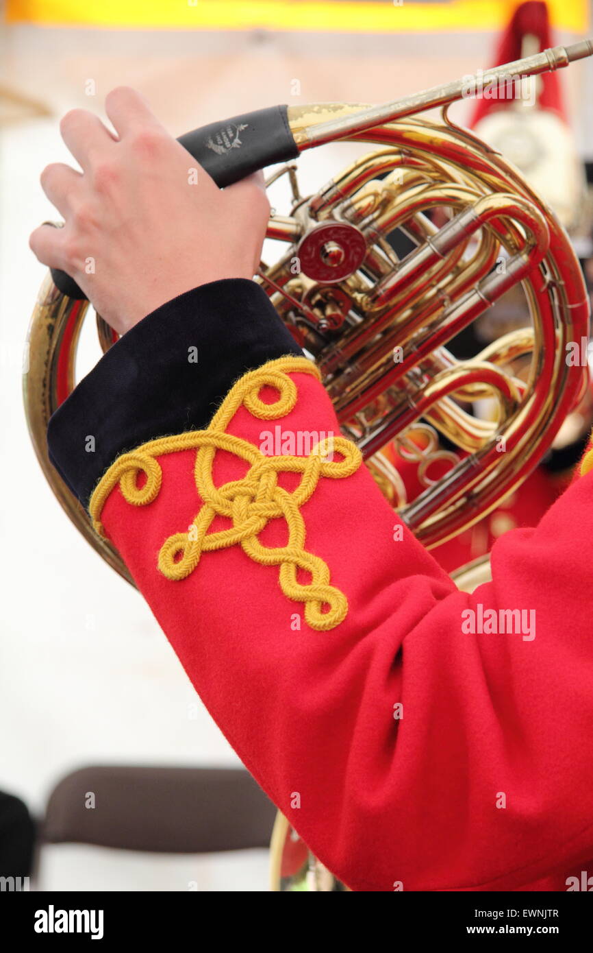 Un musicista con una banda militare soffia su di un corno francese, England, Regno Unito Foto Stock