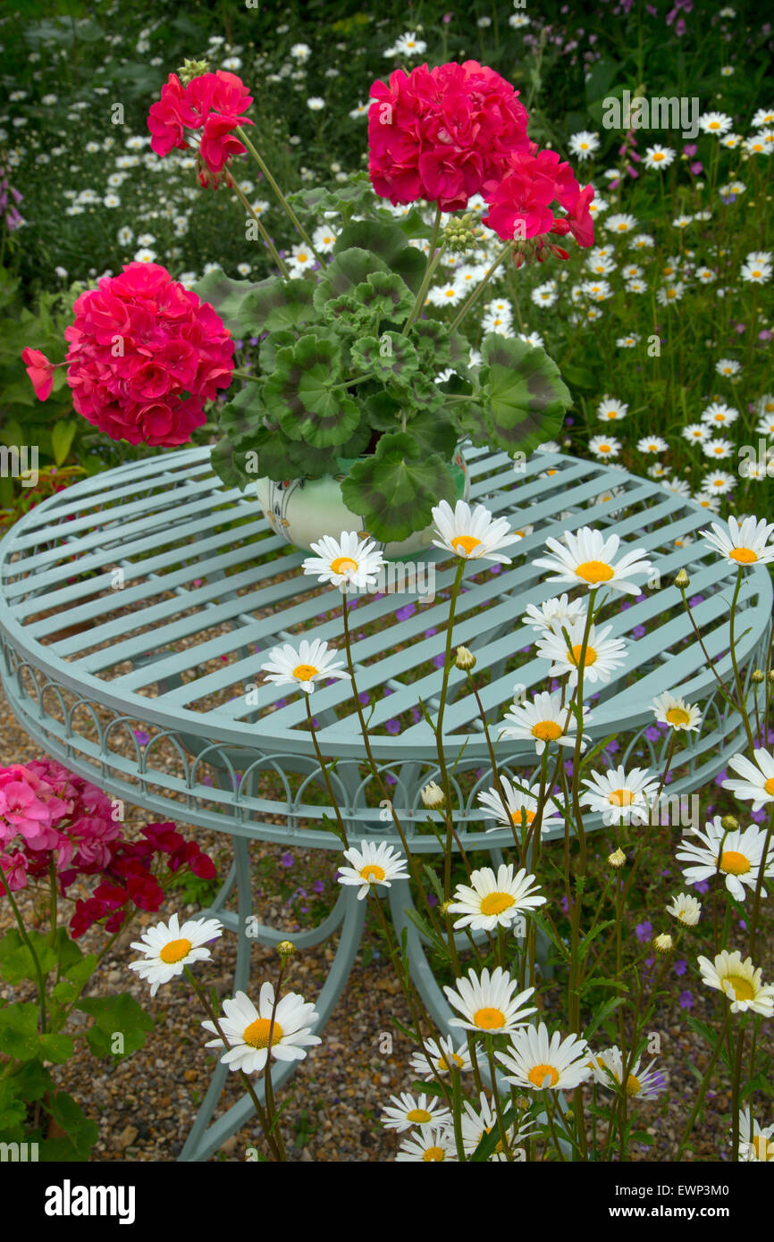 Giardino ancora in vita con gerani e blu Tavolo da giardino Foto Stock