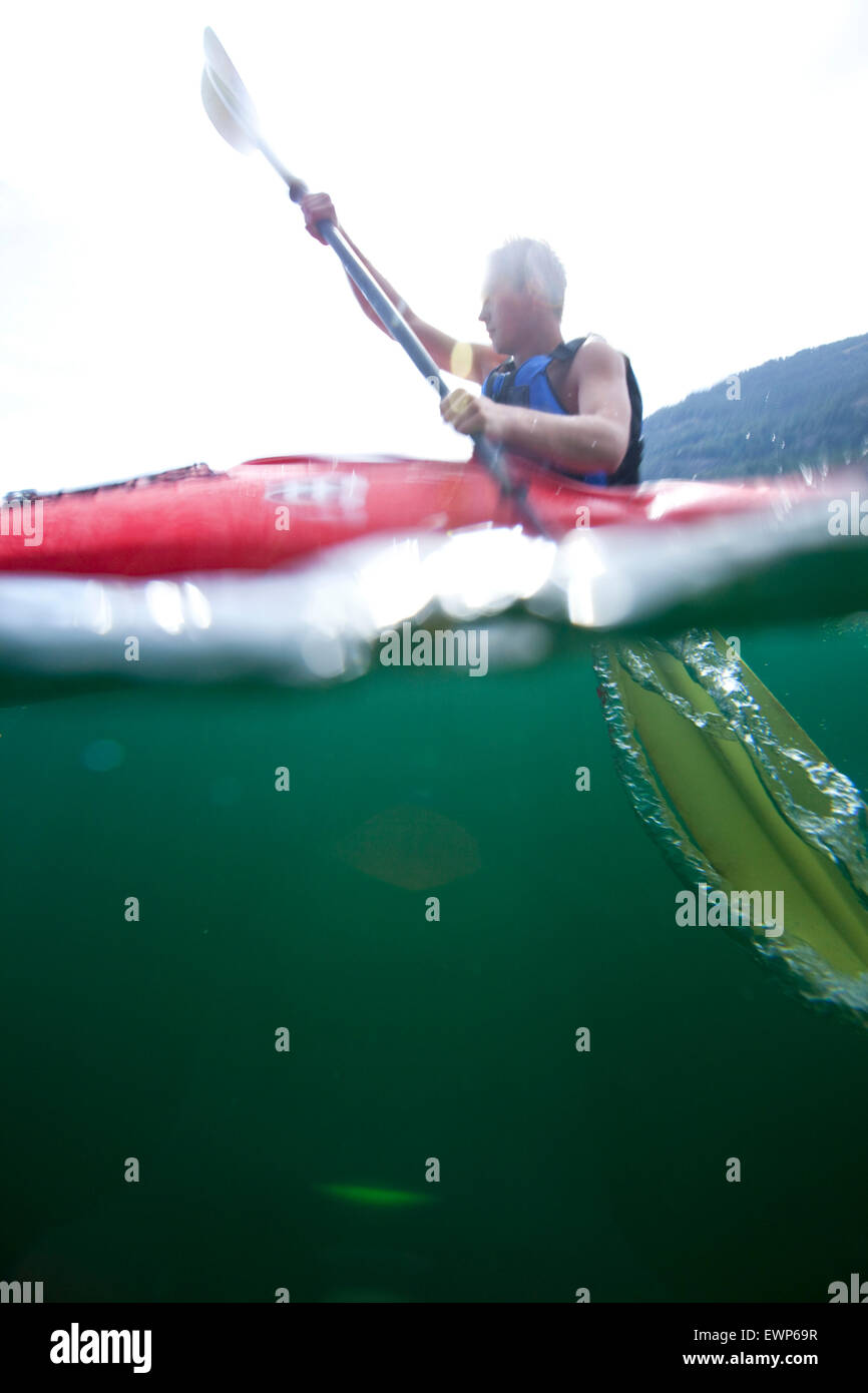 Più in vista di acqua di mare kayaker pagaiando su un lago Foto Stock