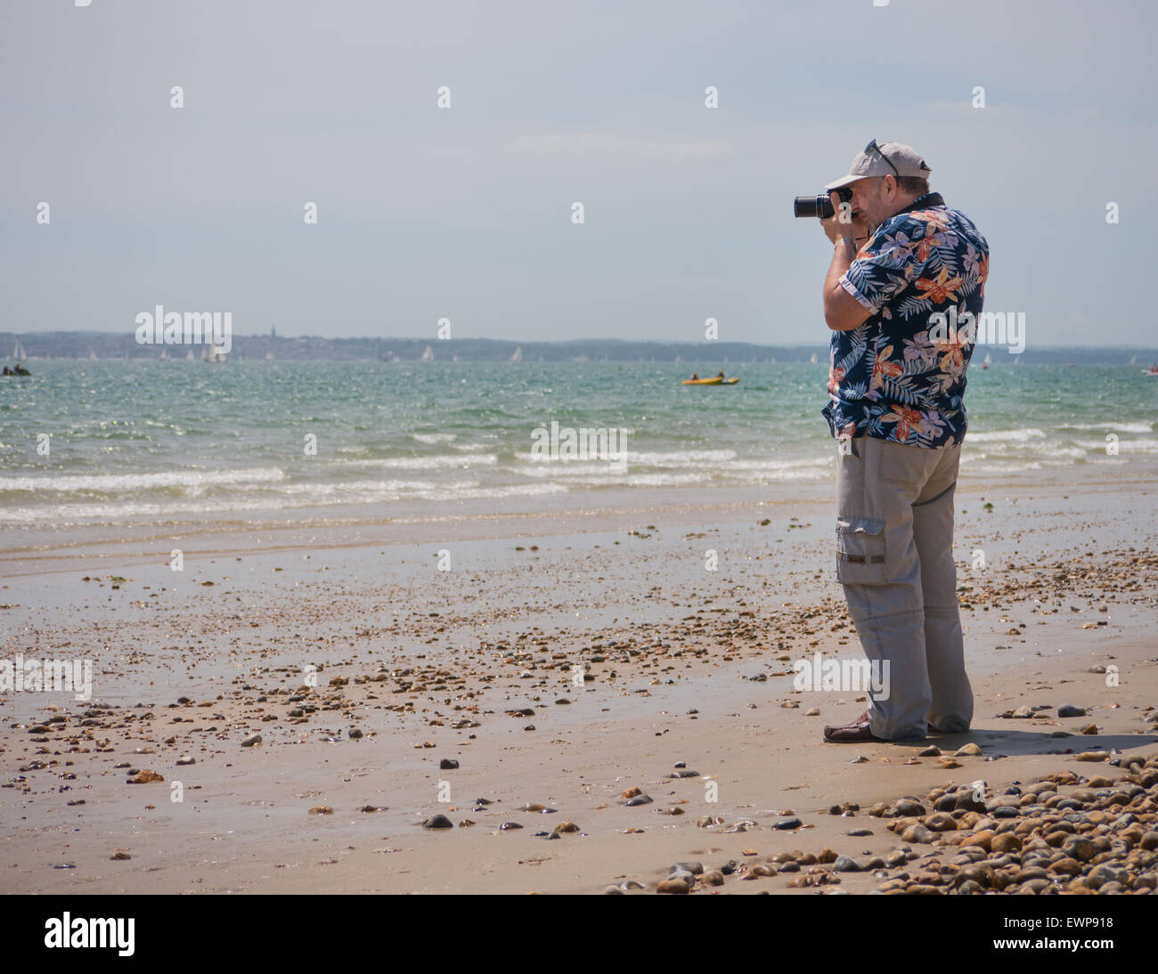 Un fotografo in una camicia hawaiana prendere le fotografie sulla spiaggia Foto Stock