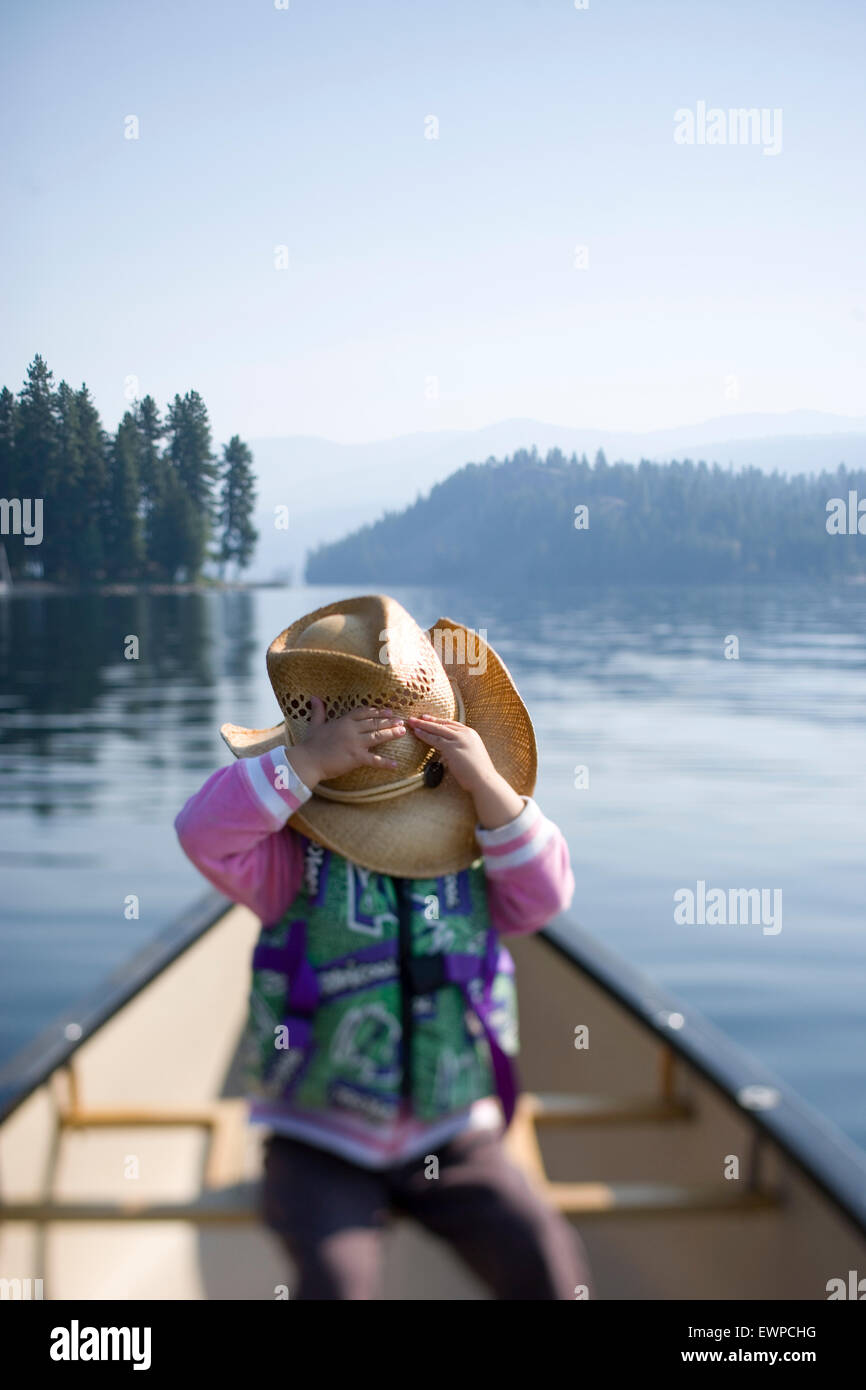Bambina in canoa nascondere sotto un cappello Foto Stock