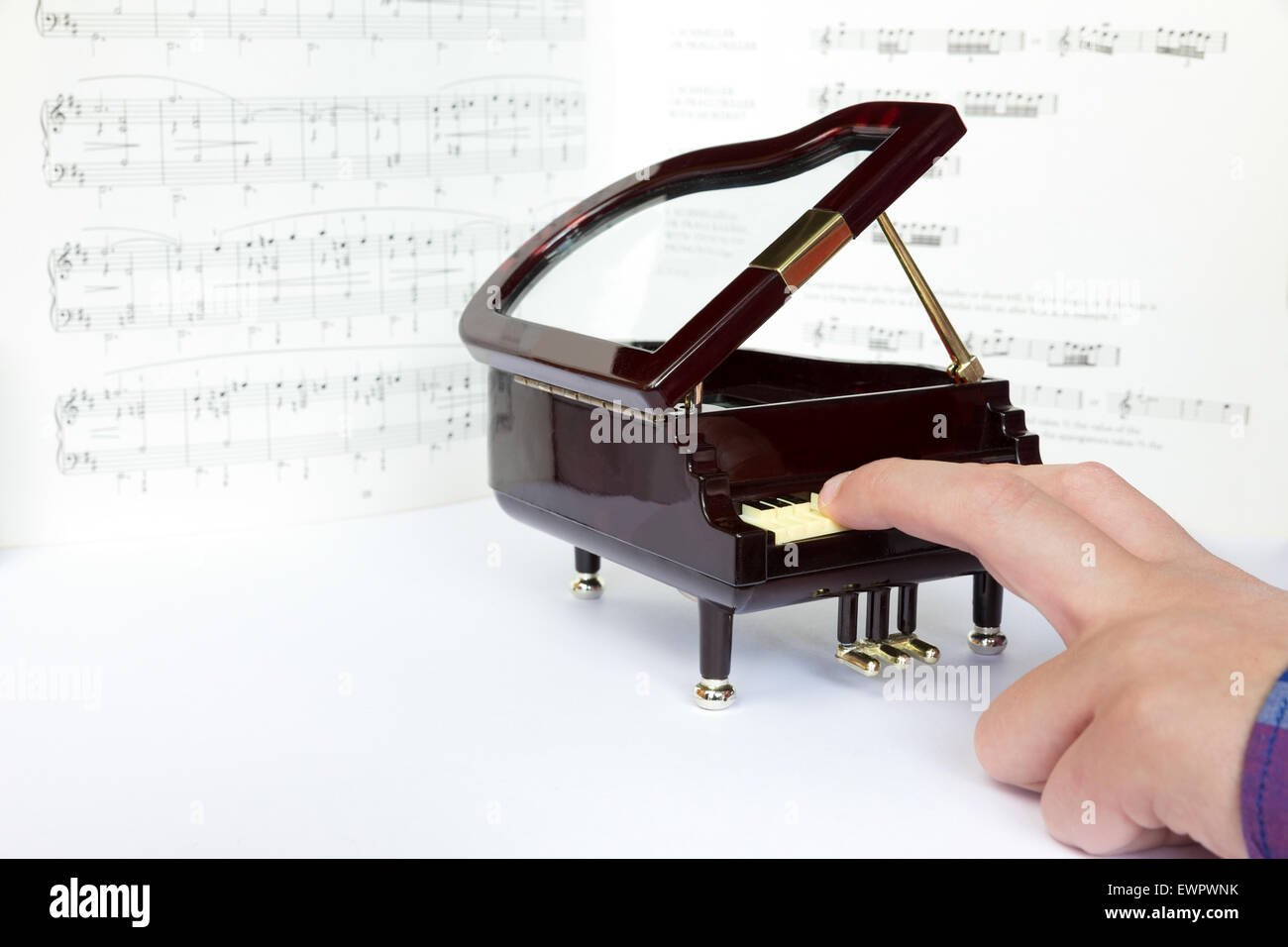Dita del bambino che gioca sul modello di piccole dimensioni di un  pianoforte con note musicali Foto stock - Alamy