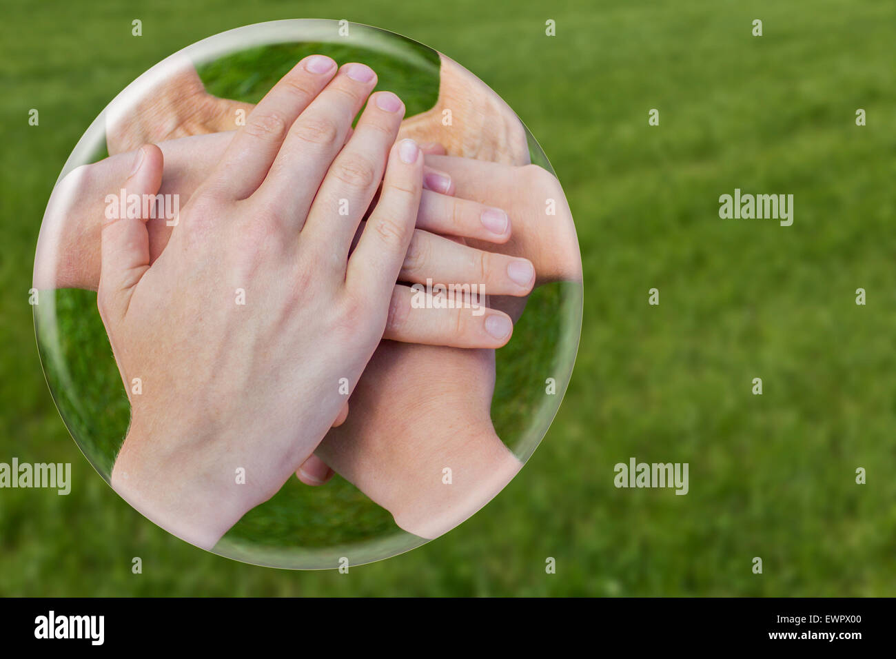 Mani che unisce la giunzione nella sfera di vetro isolato su erba verde Foto Stock