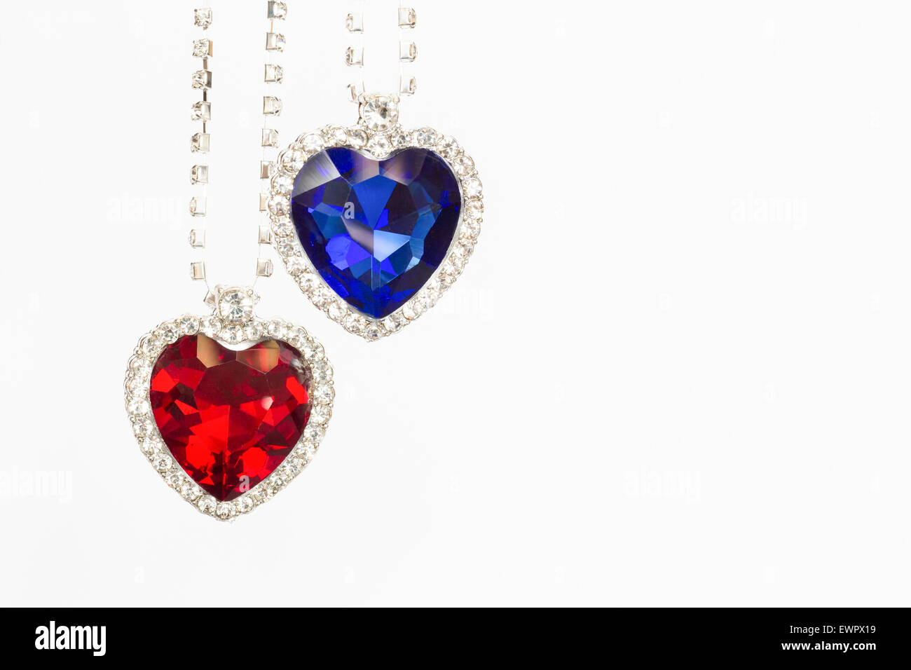 Due cuori gioielli di blu e di rosso appendere insieme come simboli isolati su sfondo bianco Foto Stock