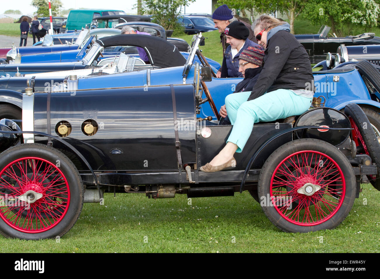 Donne alzarsi da una parte superiore aperta vintage Bugatti a una riunione esterna di automobili da collezione Foto Stock