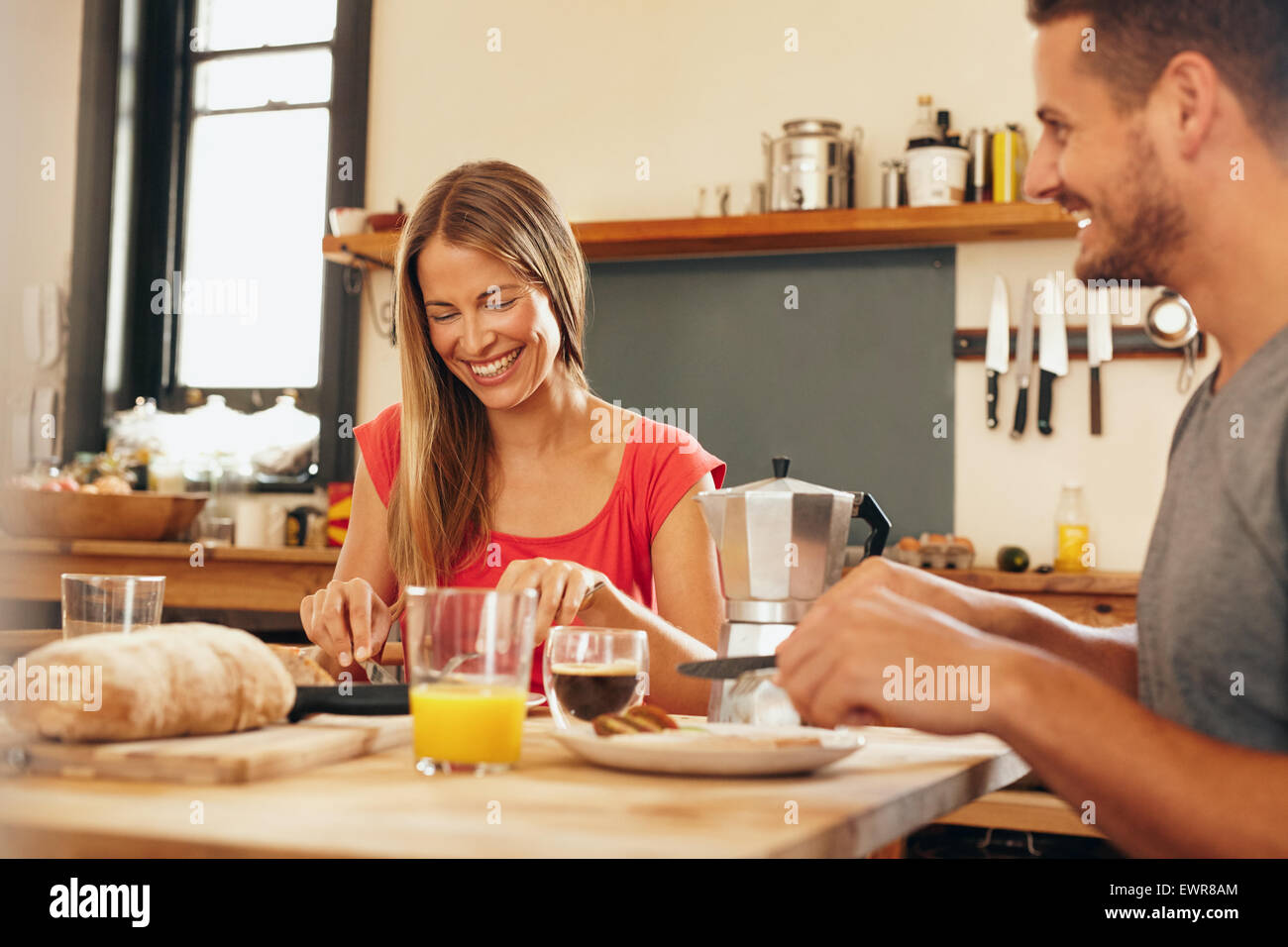 Felice coppia giovane avente la prima colazione insieme a casa. Giovane donna e uomo sorridente mentre si consuma la prima colazione nella cucina. Provvista di coppia Foto Stock