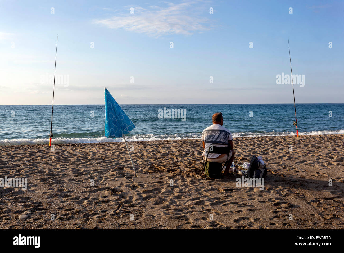 Pescatore, canne da pesca Angler seduto sulla riva del mare, mare, uomo pescato pesce spiaggia Rethymno, Creta, Grecia Foto Stock