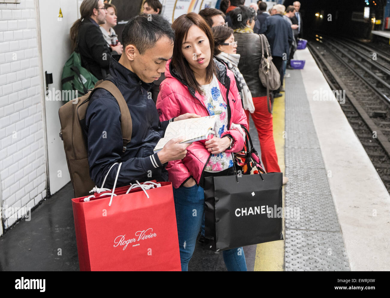 Parigi,Francia,francese,turisti cinesi,turistica, con,Chanel,branded,negozi,bag,a metro stazione ferroviaria a tarda notte dopo aver occupato il giorno di shopping. Foto Stock