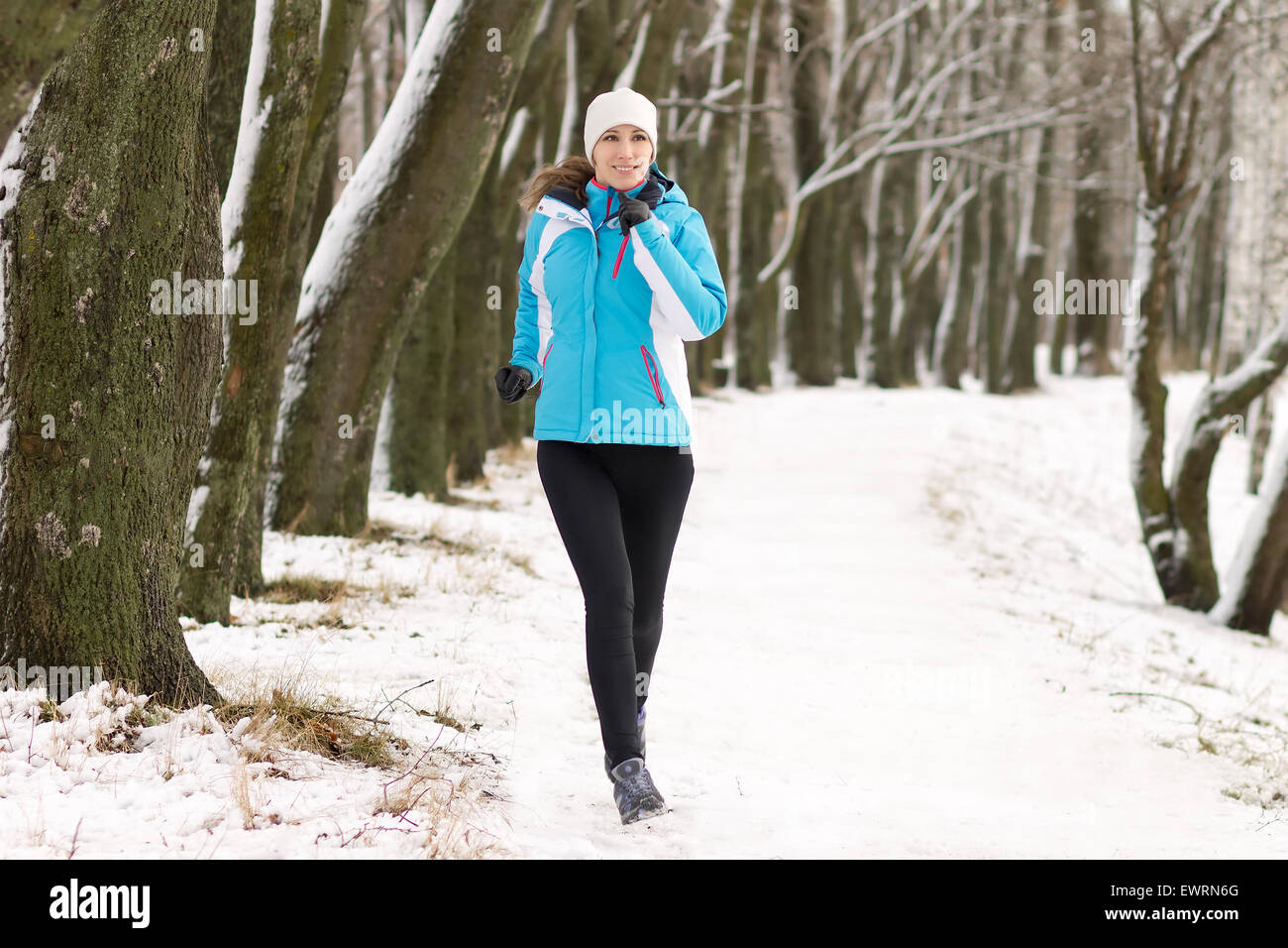 Sport Giovane donna fare jogging nel parco d'inverno. Sportive in esecuzione sul sentiero innevato Foto Stock