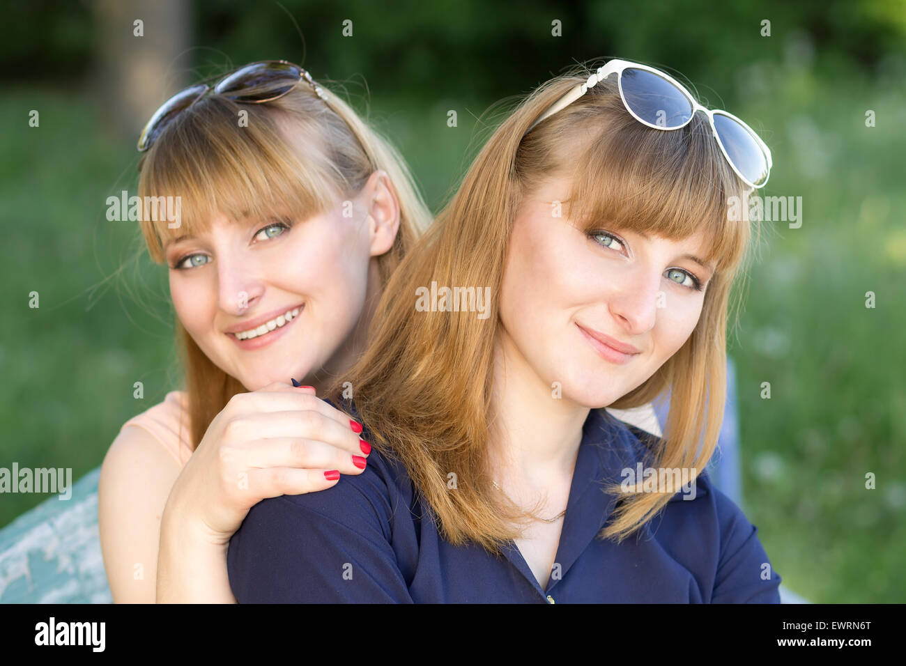 Due belle donne divertimento al summer park. Gemelli le ragazze sono in posa cercando per la fotocamera Foto Stock