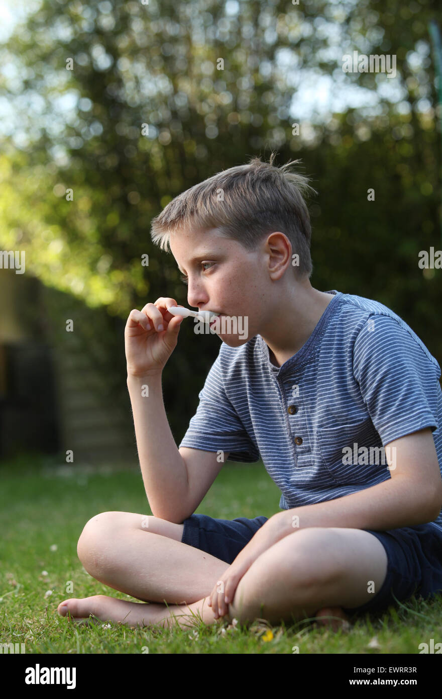 Un ragazzo di prendere la medicina antistaminico per aiutare i sintomi del raffreddore da fieno e allergie Foto Stock