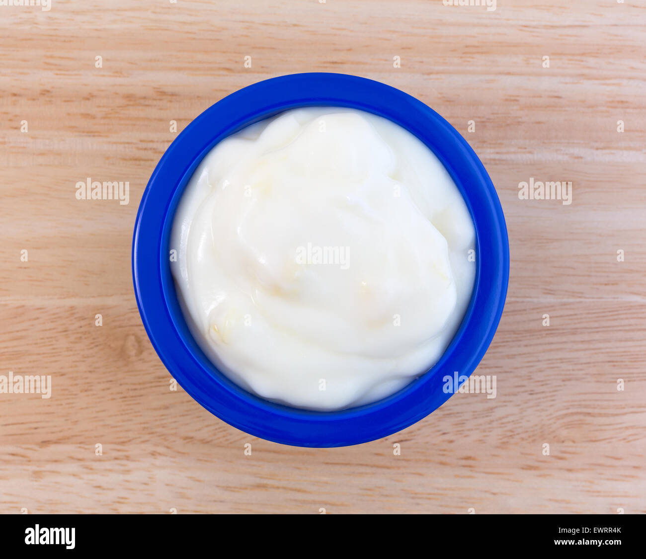 Vista dall'alto di un piccolo servizio di ananas yogurt in una piccola ciotola blu su una tavola di legno alto. Foto Stock