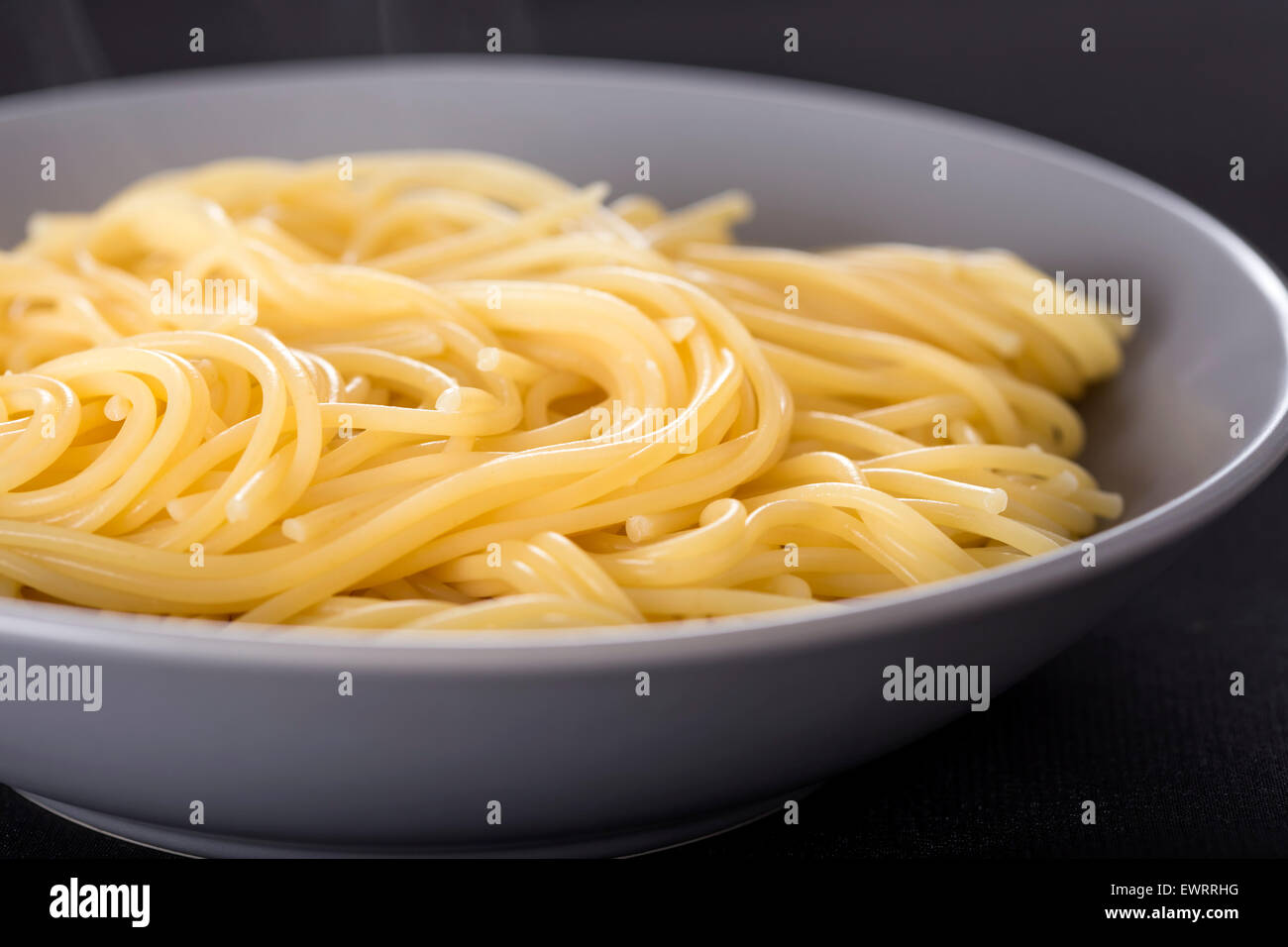 Bollite gli spaghetti italiani nella piastra su sfondo nero Foto Stock