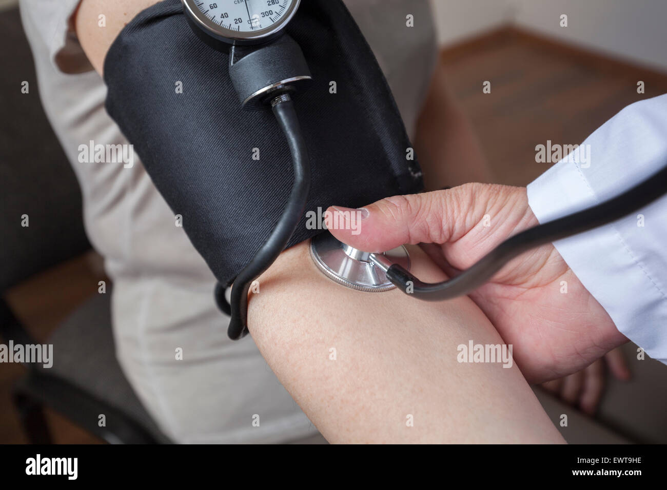 Medico cardiologo è di misurare la pressione sanguigna di donna nella sala di consultazione. Egli sta cominciando e sarà attento a notare Foto Stock