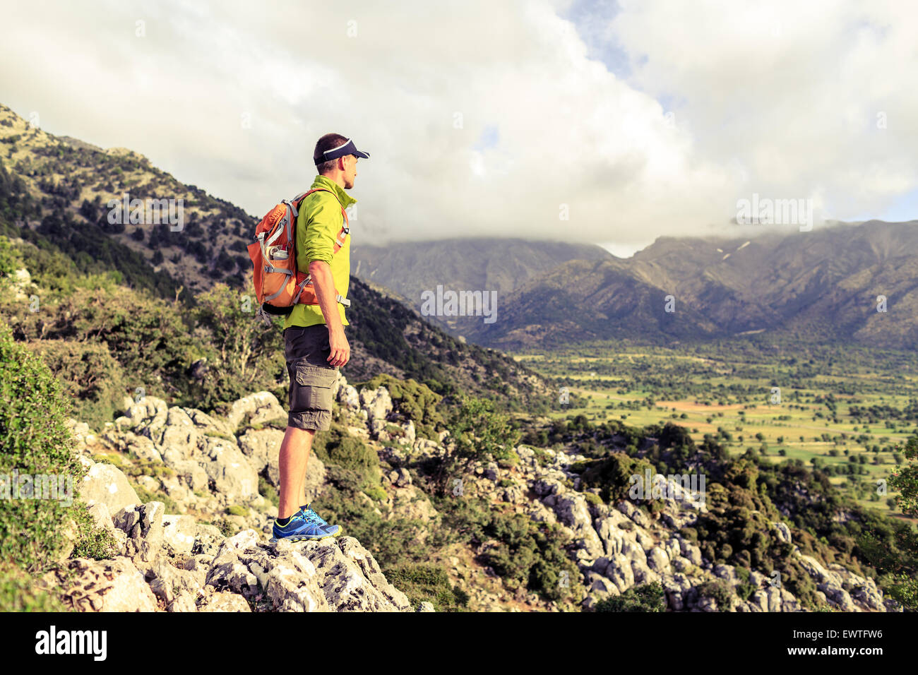Escursionismo uomo guardando belle montagne paesaggio di ispirazione. Escursionista trekking con zaino sul sentiero roccioso sentiero. Un sano Foto Stock