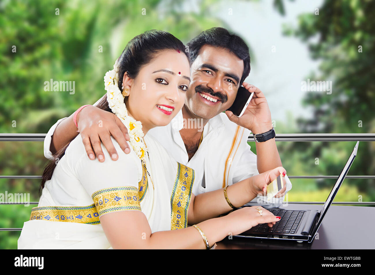 2 Indiano meridionale coppia sposata laptop carta di credito shopping e parlare per telefono cellulare Foto Stock