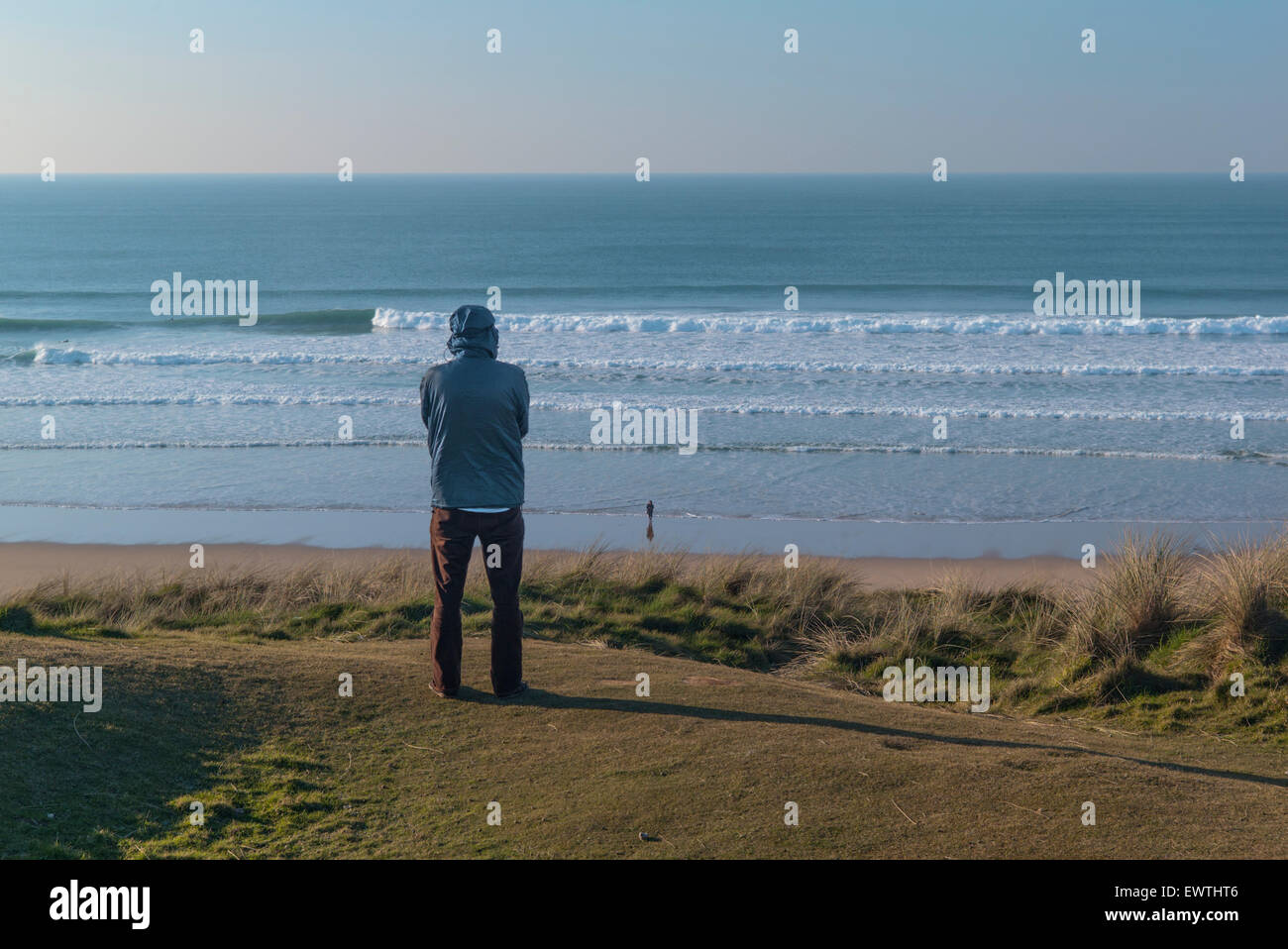 Una persona solitaria controllando il surf in Cornovaglia in una limpida giornata di blu. Foto Stock