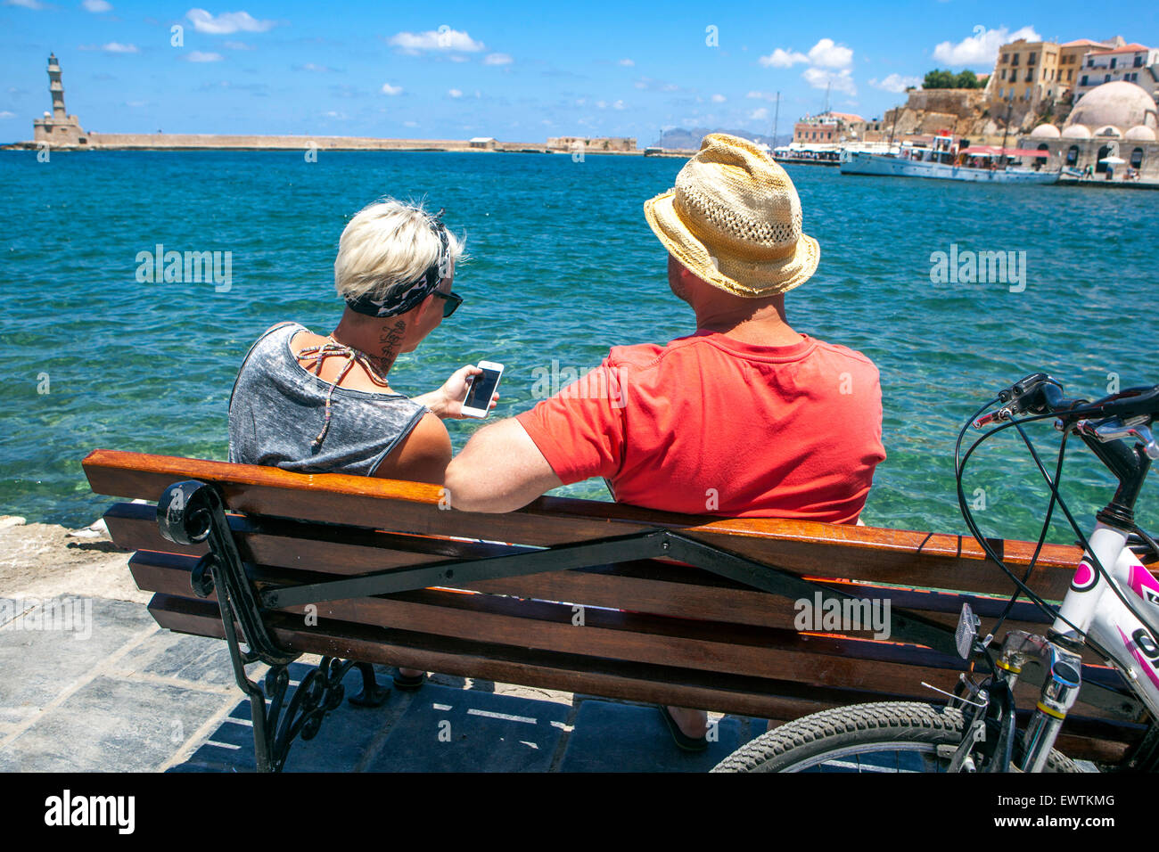Persone su una panchina Chania porto veneziano Chania Creta turisti Grecia Foto Stock
