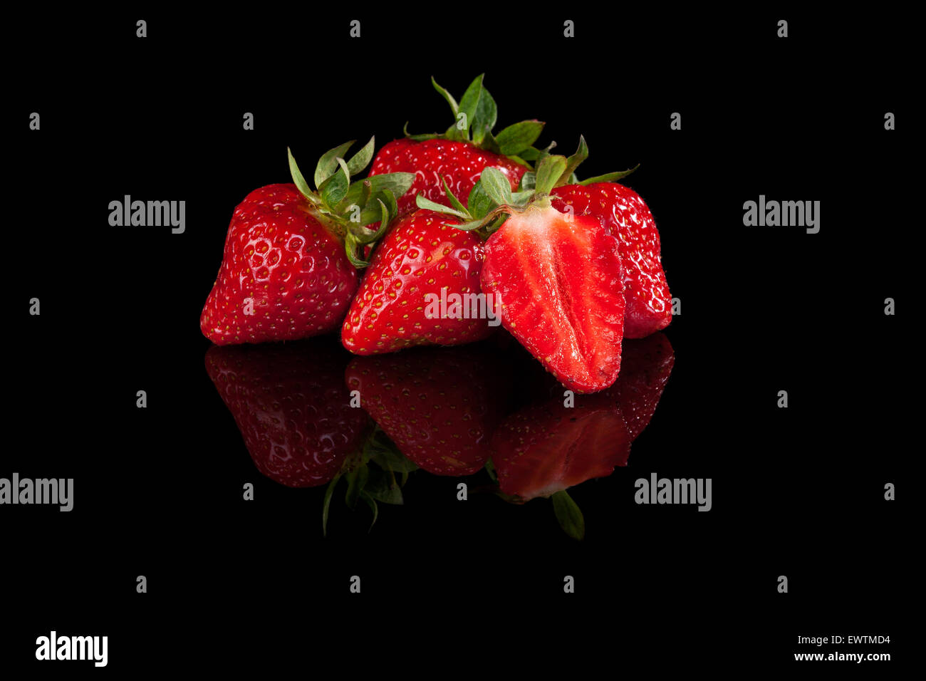 Gustose fragole isolato su sfondo nero. Una sana frutta estiva mangiare, minimo stile sparse. Foto Stock