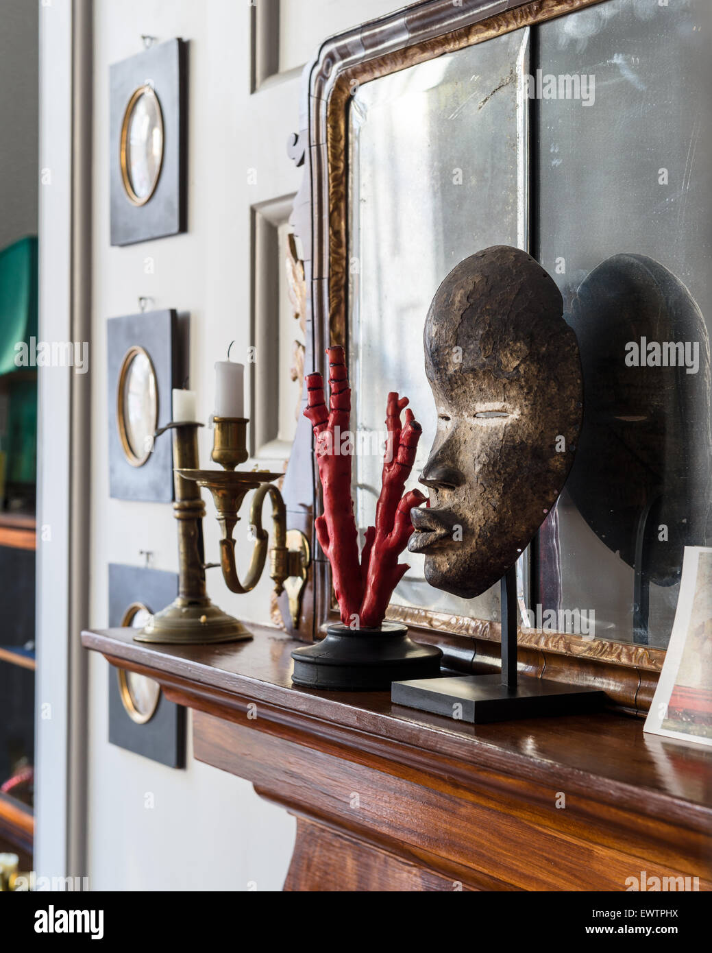 Mascherina africana sul mantelpiece con candelabri in ottone Foto Stock