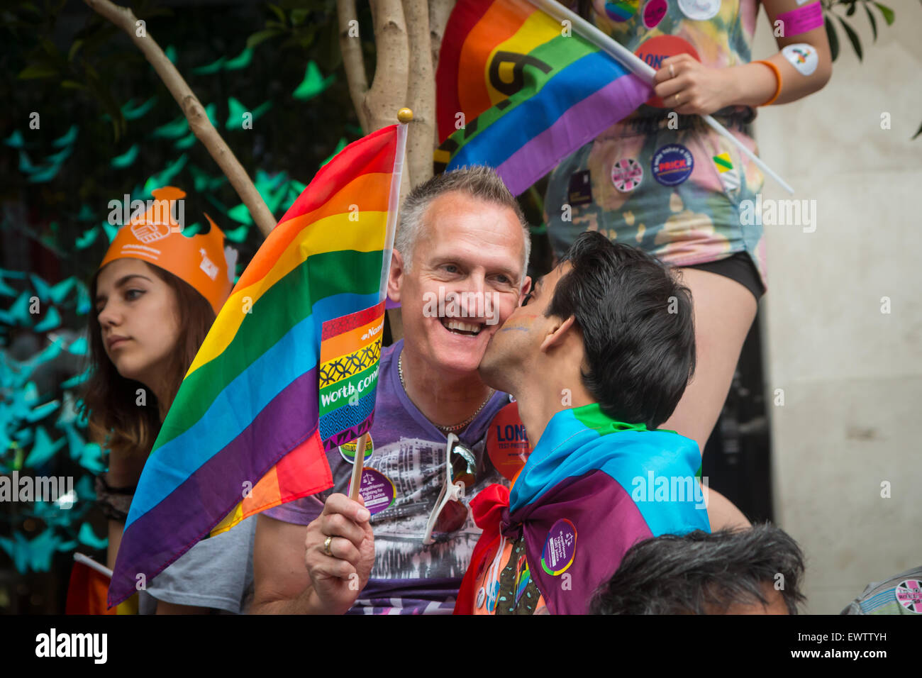 Due uomini che tengono le bandiere arcobaleno kissing al Pride di Londra 2015 Foto Stock