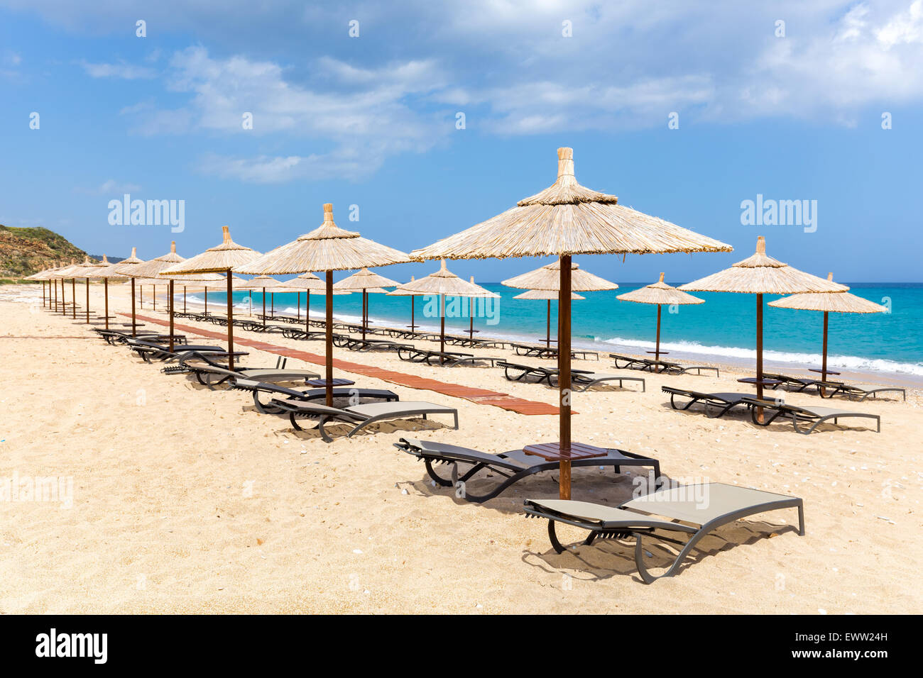 Molti reed ombrelloni in fila per ombra sulla spiaggia vuota e la costa del mare in Grecia Foto Stock