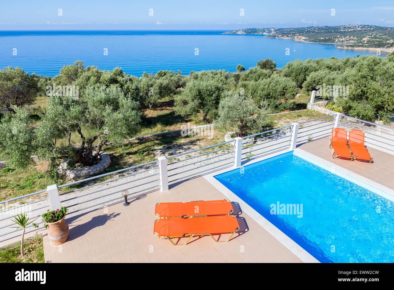 Sedie a sdraio sulla terrazza con il blu piscina vicino al mare a Costa in Grecia Foto Stock