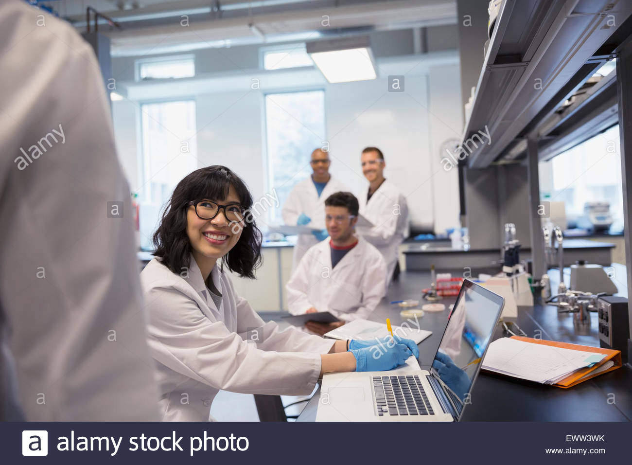 Sorridente science student in laboratorio con i compagni di classe Foto Stock