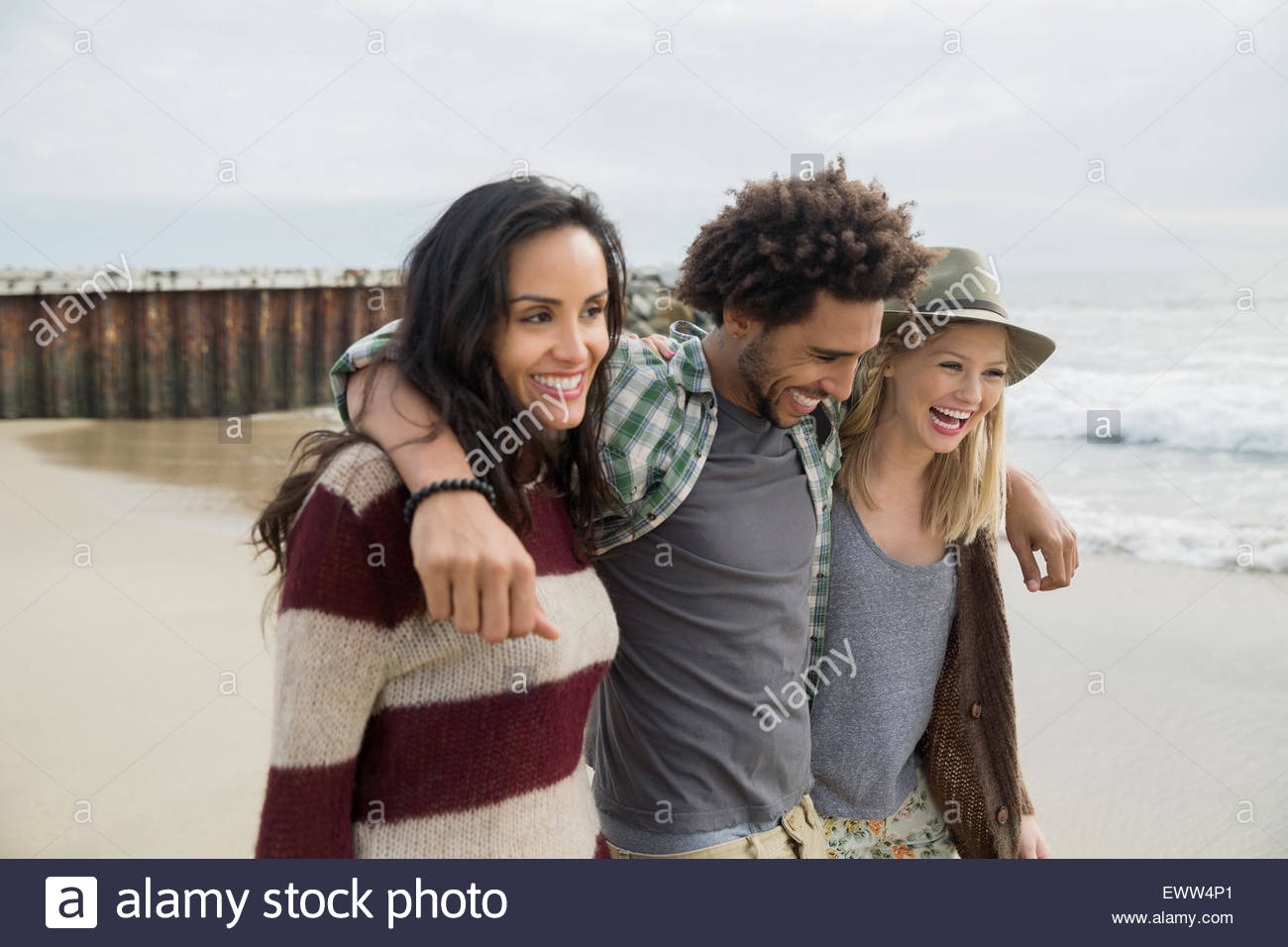 Amici di sorridere camminando in una fila sulla spiaggia Foto Stock