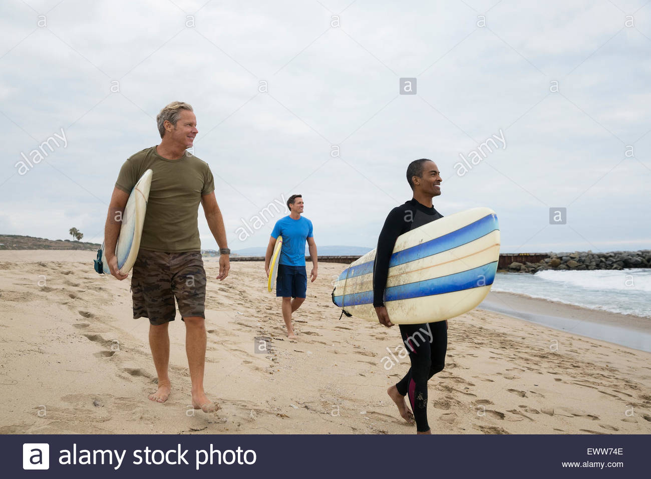 Gli uomini con tavole da surf a piedi sulla spiaggia Foto Stock