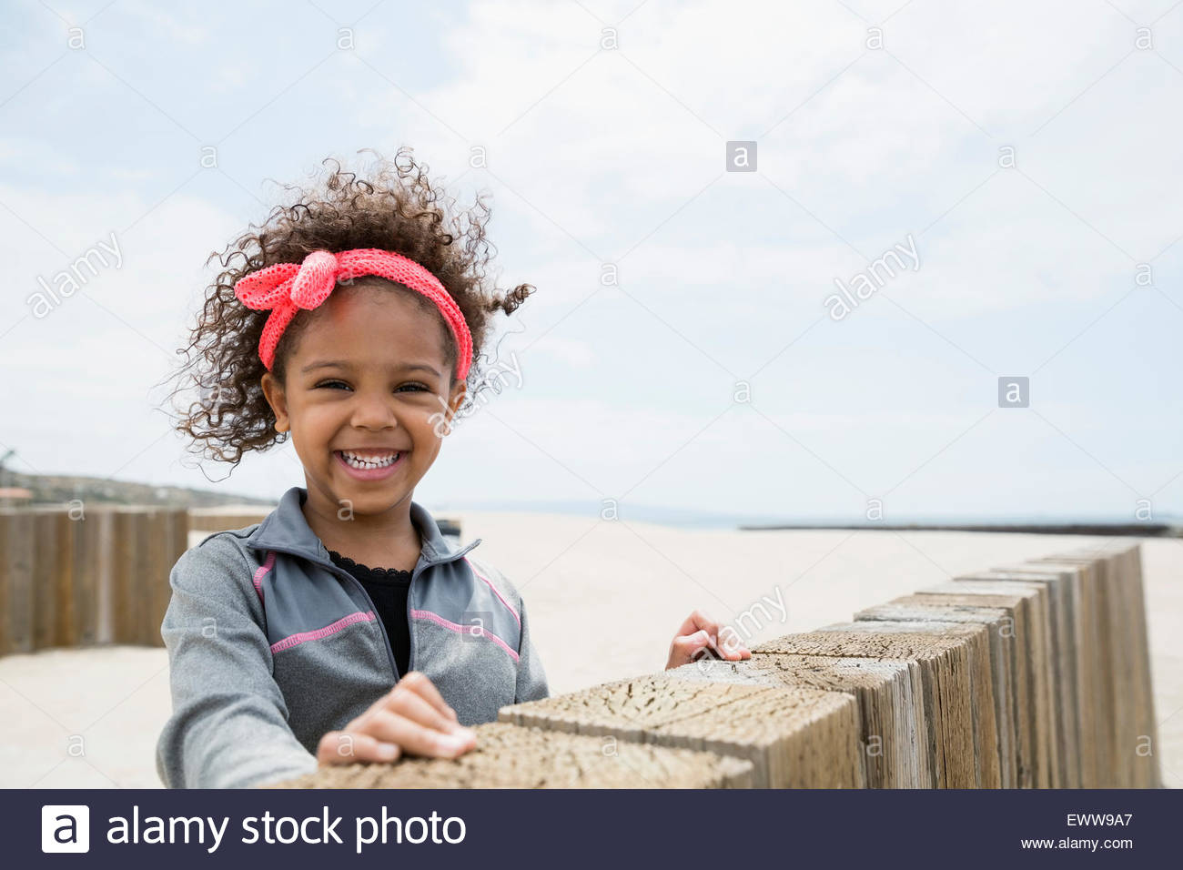 Ritratto sorridente ragazza capelli ricci a parete in spiaggia Foto Stock