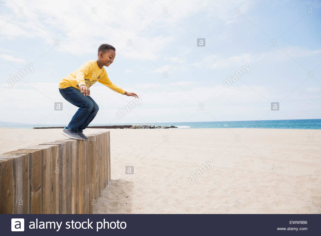 Ragazzo che salta da parete in spiaggia Foto Stock