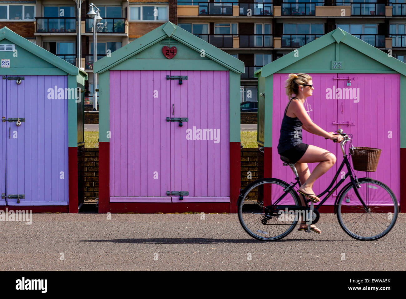 Un ciclista passa di pittoresca spiaggia di capanne sul lungomare di Brighton, Brighton, Sussex, Regno Unito Foto Stock