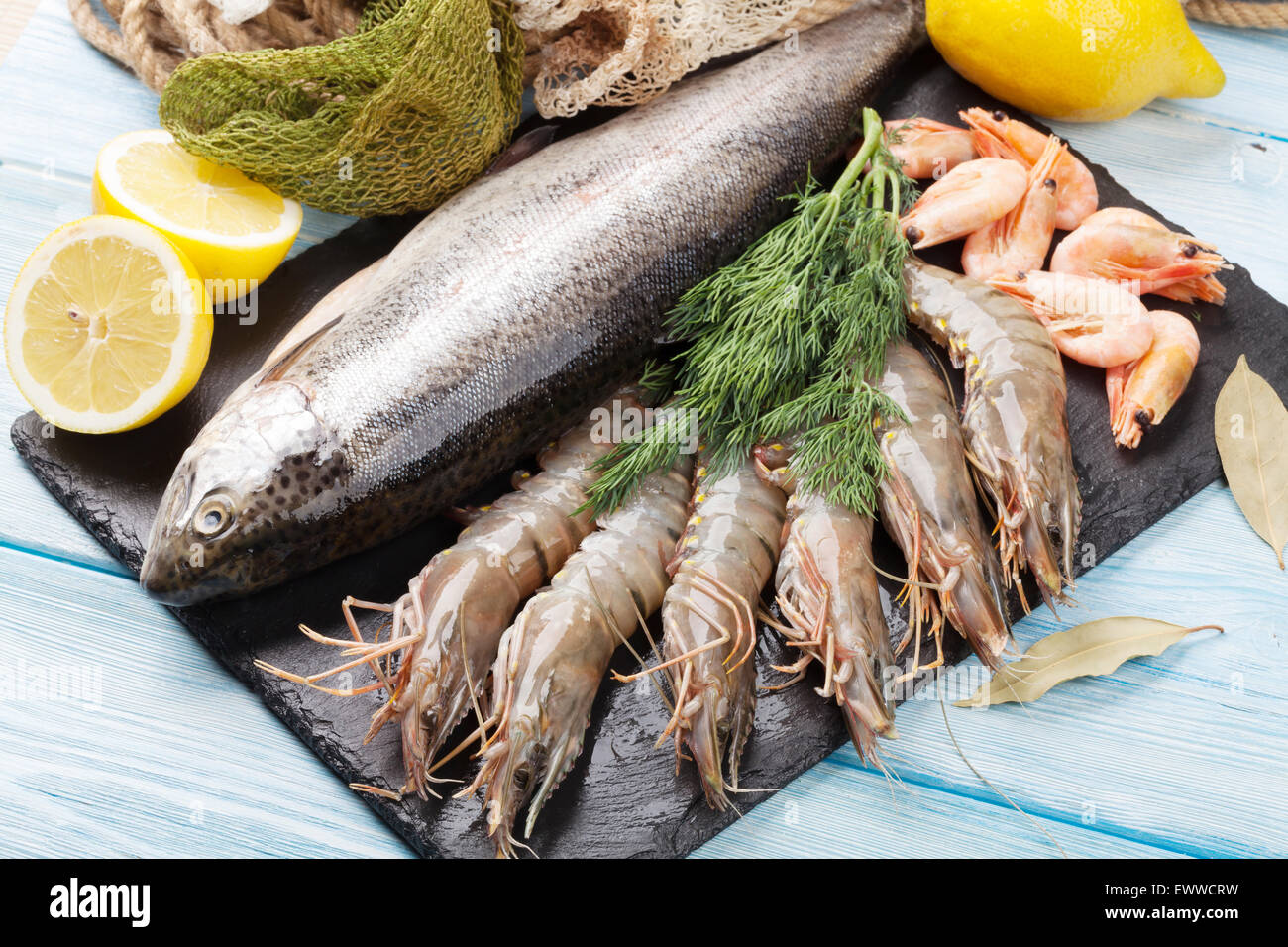 Crudo fresco il cibo del mare con spezie sulla lastra di pietra su un tavolo di legno dello sfondo. Vista superiore Foto Stock
