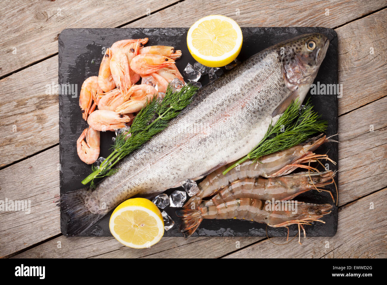 Crudo fresco il cibo del mare con spezie sulla lastra di pietra su un tavolo di legno dello sfondo. Vista superiore Foto Stock