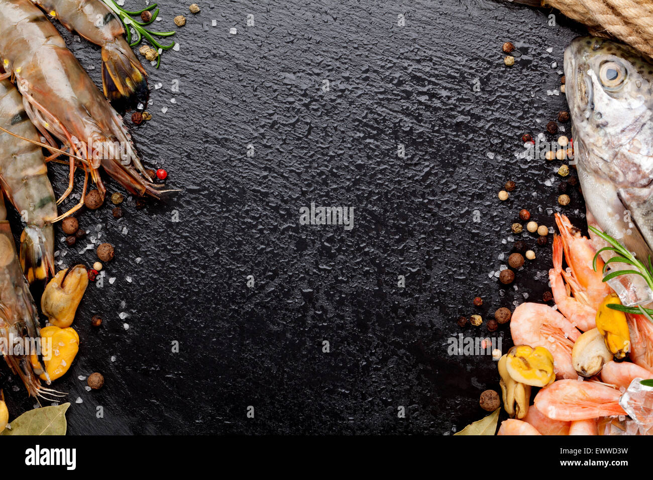 Crudo fresco il cibo del mare con spezie sulla pietra nera dello sfondo. Vista da sopra con lo spazio di copia Foto Stock