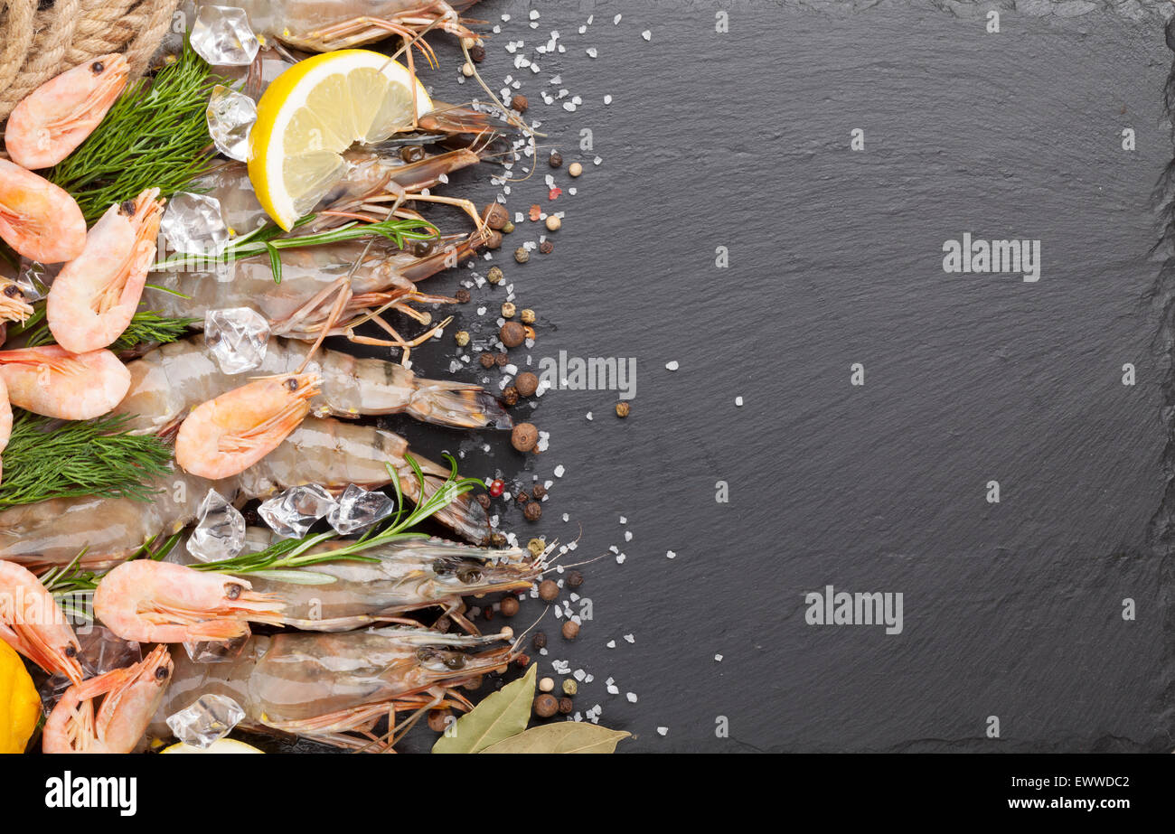 Gamberetti freschi con spezie sulla pietra nera dello sfondo. Vista da sopra con lo spazio di copia Foto Stock