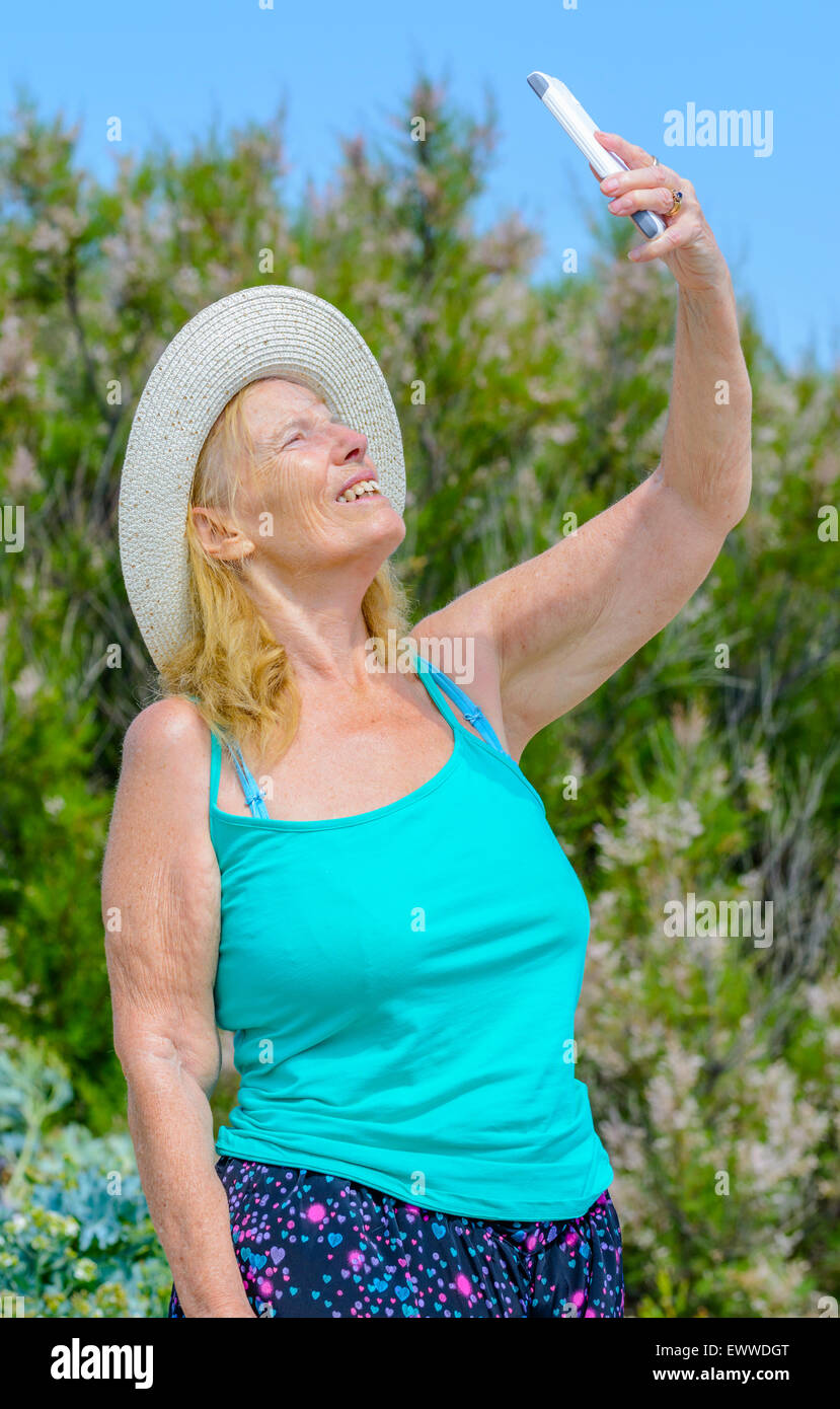 Donna di mezza età tenendo un selfie foto di se stessa in una calda giornata di sole in estate nel Regno Unito. Foto Stock
