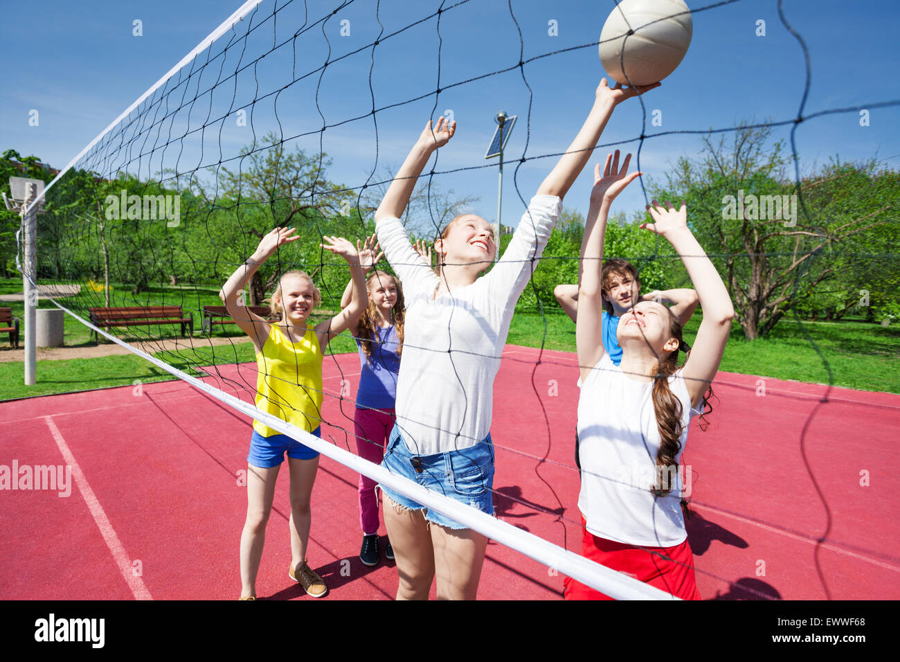 Gli adolescenti in movimento con le braccia in alto giocare a pallavolo Foto Stock