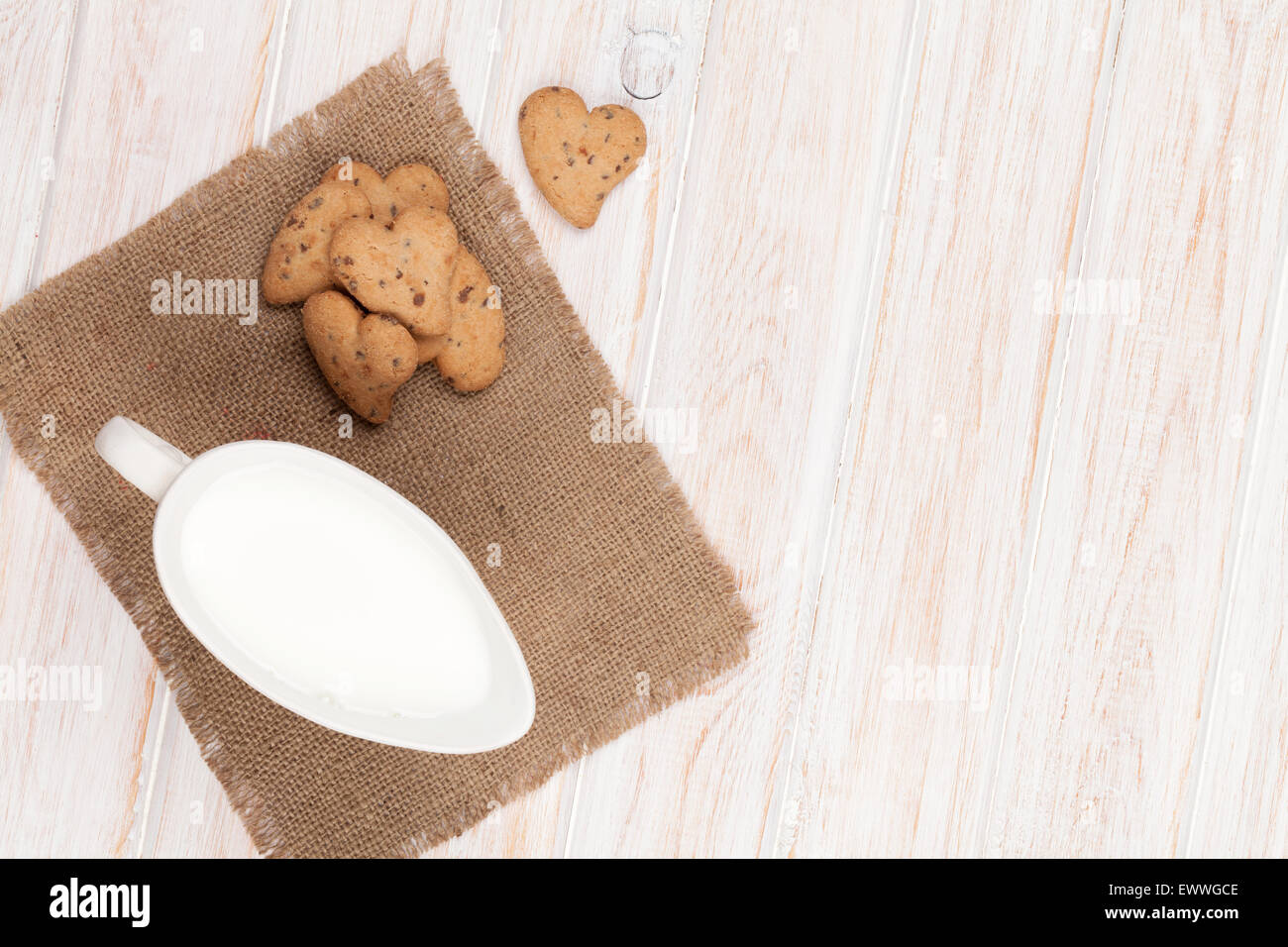 A forma di cuore ad gingerbread cookie e la brocca del latte. Su bianco tavolo in legno Foto Stock