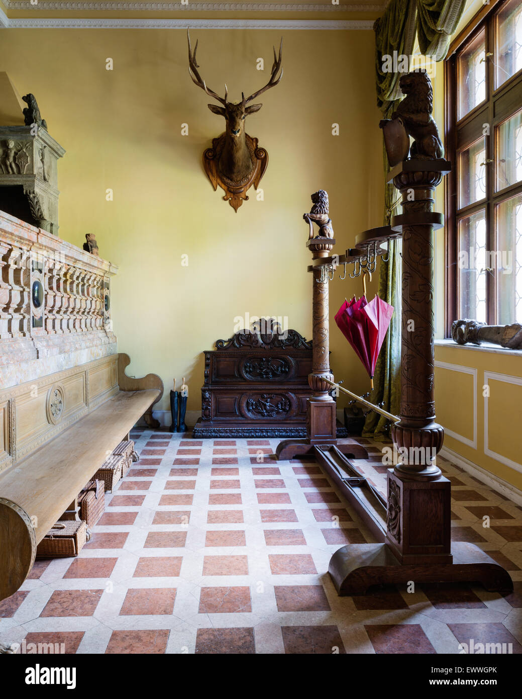 Rivestimento di ornati e portaombrelli in castello guardaroba con montata la testa di cervo e di legno lunghi ad alta sostenuta da banco Foto Stock