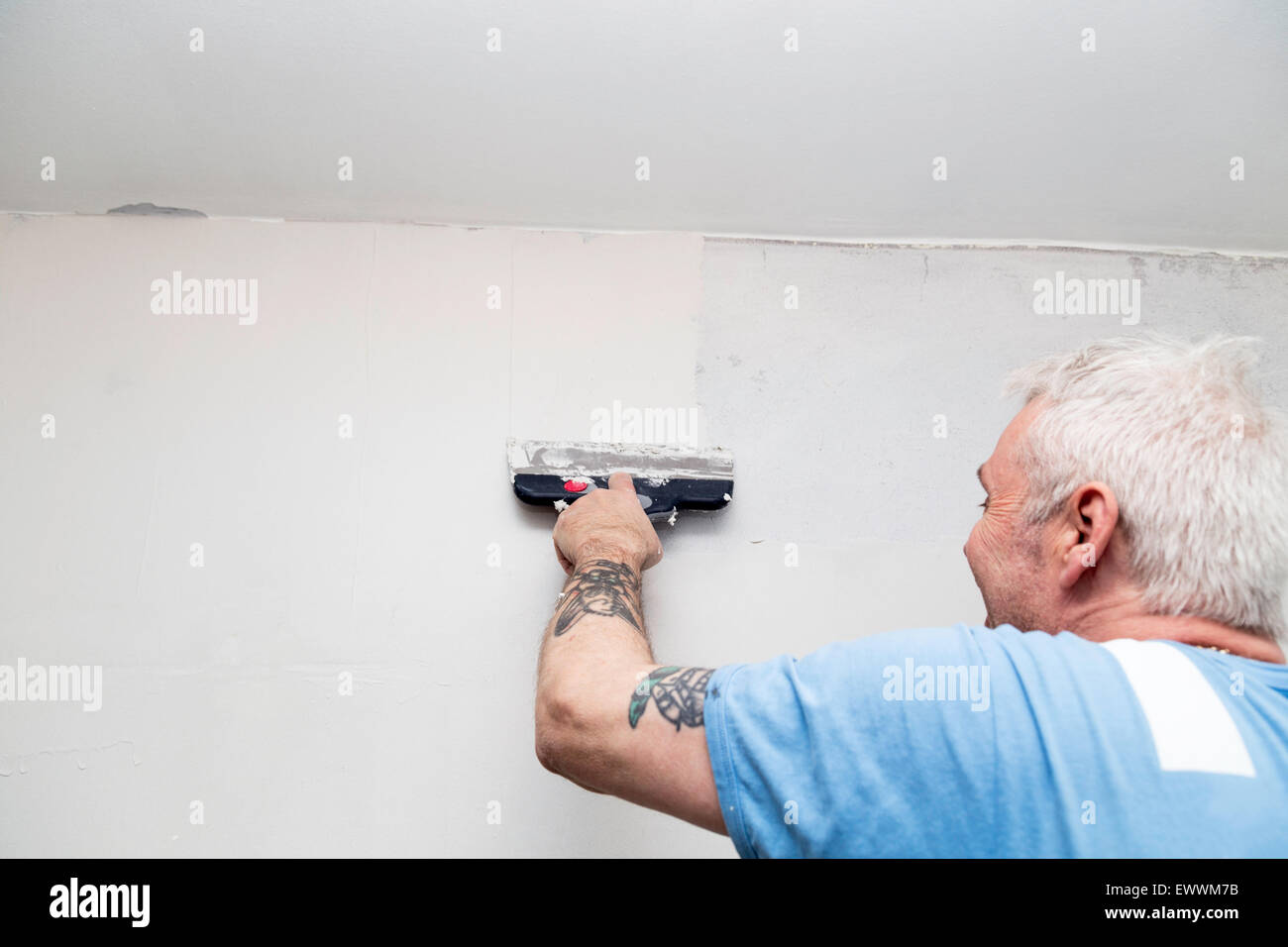 Pittore spackling un muro di cemento nella preparazione prima della verniciatura Foto Stock