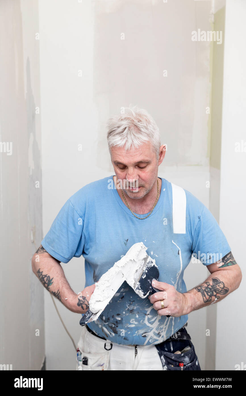 Pittore professionista lavora con spackle prima che dipinge le pareti un progetto di ristrutturazione di una casa Foto Stock