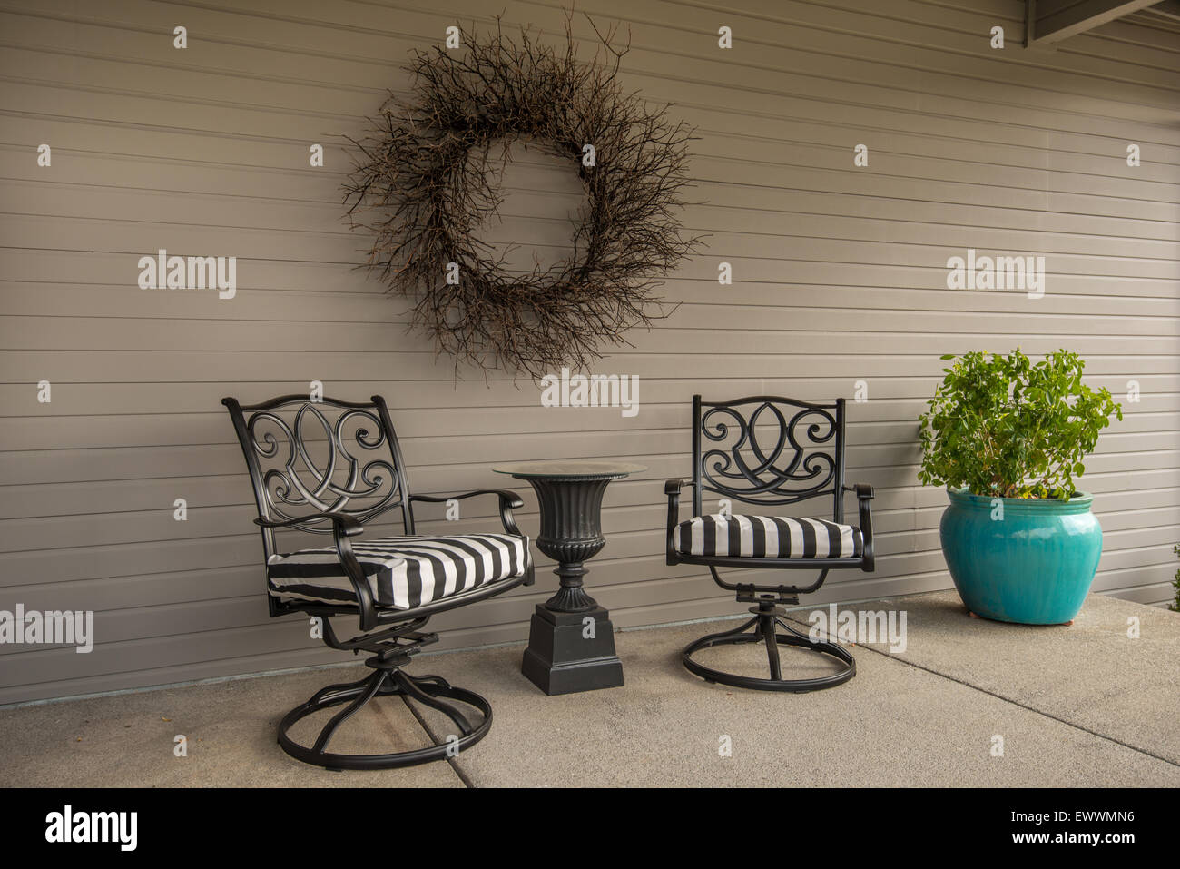 Patio girevole sedie, top in vetro tavolo e ramoscello wreathe su open-air veranda Foto Stock