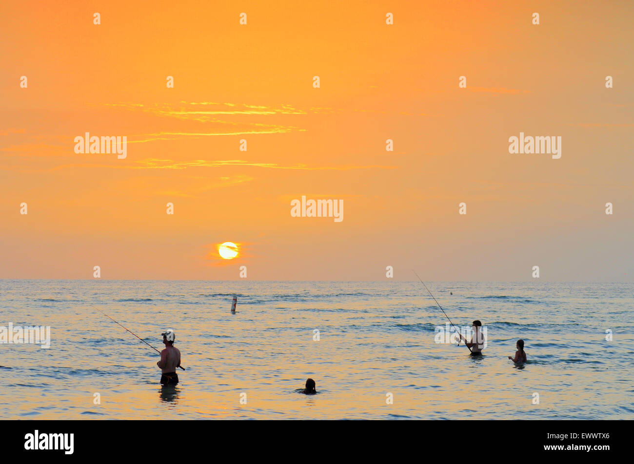 Bradenton Beach, Florida, Stati Uniti. 1st luglio 2015. Il sole si rompe al Tramonto dopo una giornata calda e umida colta negli anni '90. Pesca e nuoto nella calda acqua del Golfo Foto Stock