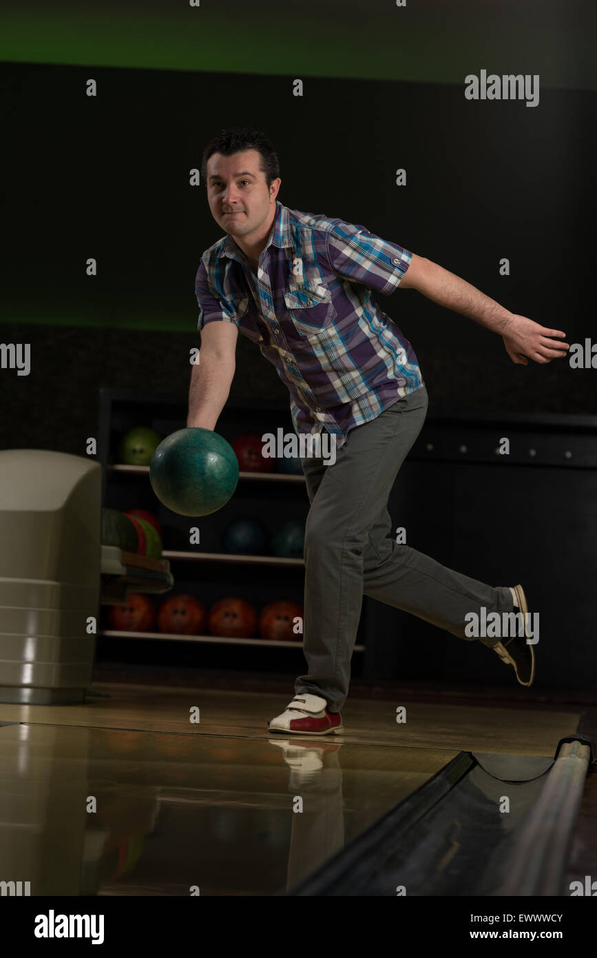 Sorridente giovane uomo giocando con una palla da bowling Foto Stock