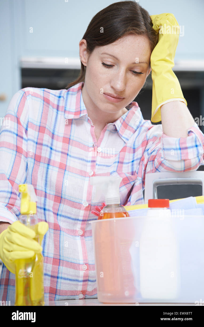 Infelice Donna circondata da prodotti di pulizia a casa Foto Stock